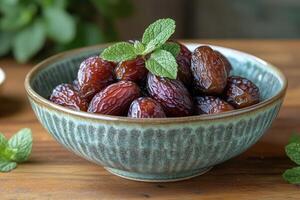 A bowl of dates with mint leaves on a table photo