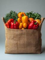 A burlap bag filled with various colorful vegetables, showcasing fresh produce. photo