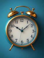 A vintage-style alarm clock with a turquoise body and gold accents against a blue background. photo