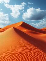 A scenic view of orange sand dunes under a blue sky with fluffy clouds. photo