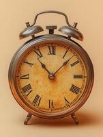 A vintage alarm clock with Roman numerals on a soft orange background. photo