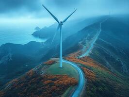 A scenic view of a wind turbine on a misty coastline, surrounded by lush hills and ocean. photo