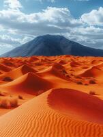A stunning desert landscape featuring orange dunes under a blue sky with distant mountains. photo
