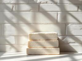 Three stacked blocks of a light-colored substance against a textured wall with shadows. photo