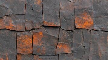 Textured Dark Grey and Orange Stone Wall Background Rugged Irregular Rock Surface Detail photo