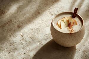 Smoothie features fresh apple slices topped with a cinnamon stick and a sprinkle of cinnamon, set against a warm beige background, evoking a nostalgic seasonal feel photo