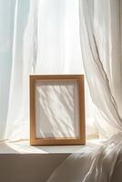 A light oak picture frame rests on a windowsill, surrounded by sheer white curtains that sway softly. Natural light pours in, creating a tranquil atmosphere perfect for adding a personal touch photo