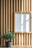 A stylish light wood picture frame sits against a wall of vertical wooden slats. A small green plant adds a touch of nature to the space, creating a calm atmosphere photo