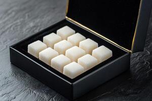 Handcrafted sugar cubes are elegantly showcased in a velvet-lined box with gold foil detailing. The smooth surface creates a luxurious backdrop, ideal for sophisticated presentations photo