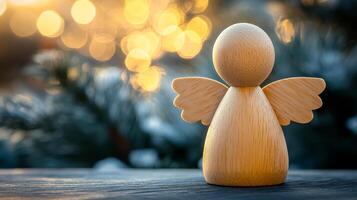 A wooden angel is sitting on a table. The angel is small and has wings. The background is blue and has a snowy appearance photo