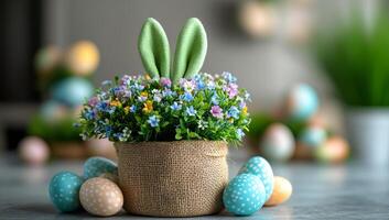 A basket of Easter eggs and flowers sits on a table. The basket is filled with a variety of eggs, including some with polka dots, and a small plant with green bunny ears. The flowers are colorful photo