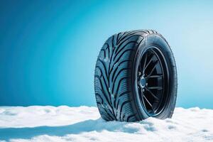 Winter tire resting on snow with a clear blue backdrop highlighting its design and texture during daylight hours photo
