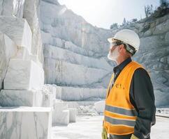 Marble quarry worker examining stone blocks under bright sunlight in an active quarry site photo