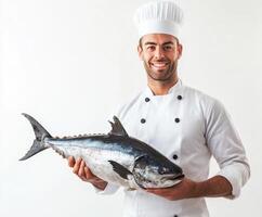 Chef proudly holds a large fresh tuna fish while smiling in a bright kitchen setting, showcasing culinary expertise and passion photo