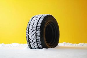 Snow-covered tire against a bright yellow background in a winter setting photo