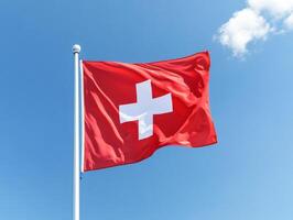 Swiss flag waving in the bright blue sky during a sunny day in Switzerland photo