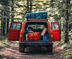 Back of a red truck loaded with camping gear in a forest setting during the day photo