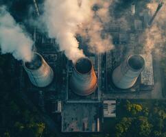 Smoke billows from cooling towers at an industrial facility during the late afternoon in an urban setting photo