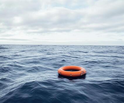 Bright orange life ring floating alone in calm ocean under cloudy sky photo