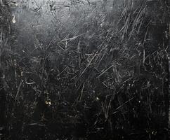 Textured black surface with scratches and marks showcasing wear and age in a dimly lit setting photo
