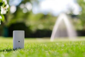 Smart garden sensor on lush green lawn with water fountain in background photo