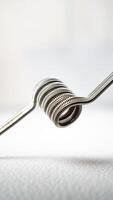 macro close up photo of vaping vaporizer single coil wire alien core coil, twisted messes coil in aluminum stainless steel on white background
