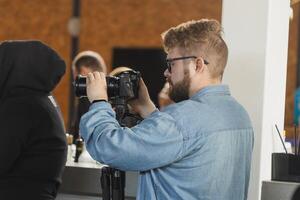 Man videomaker works on news conference modern camera with a digital display recording an interview on event. Mass media and television and technology concept photo
