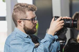 Man videomaker works on news conference modern camera with a digital display recording an interview on event. Mass media and television and technology concept photo