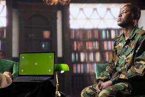 African american army veteran discusses anxiety next to green screen with a counselor, representing mental health care for PTSD and war related stress disorder. Shell shock support. photo