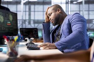 Annoyed engineer in data center getting access denied notification on PC screen, trying to access important files after they were locked by hacker using ransomware, doing face palm hand gesturing photo