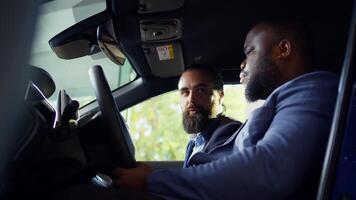 Customer discussing with sales executive concerns noticed after driving car during test drive. African american man talking with showroom salesman, telling him observed issues in vehicle, camera B photo