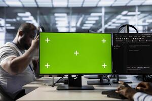 Data center expert using green screen PC to write disaster recovery plans ensuring minimal downtime. Server farm worker uses mockup computer display to monitor performance photo
