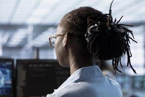 Woman sitting at computer desk, finishing programming tasks in AI data center used for machine learning training. Close up shot of engineer upgrading artificial intelligence tech photo