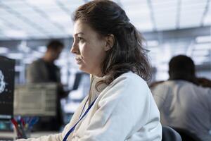 Computer scientist working in high tech server hub capable of processing vast amounts of data. Close up shot of woman at PC typing on keyboard, updating servers controlling network resources photo