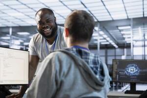 Engineer having fun with colleague at work in data center establishment, making jokes. Team of technicians making each other laugh, bonding in server room, taking break from job photo