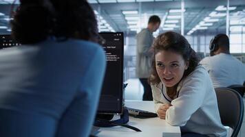 Happy technician chatting with colleague while doing maintenance on artificial intelligence neural networks. Jolly admin talking with coworker while using AI systems aiding processing, camera B photo