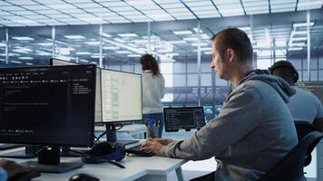 Engineer starting job shift in server hub used for processing vast amounts of data. IT programmer arriving at work in data center, sitting at PC desk, typing on keyboard, camera B photo