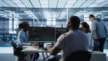 Admin programming in server room housing advanced equipment storing massive datasets. Developer typing code on PC to mend data center racks doing complex computational operations, camera B photo