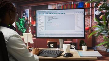 Woman in home office looking at UI on PC screen, typing and executing programming code. Coding application UI used by IT developer writing and testing code in modern apartment, camera A photo
