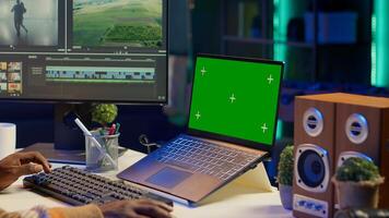 Videographer creating visual effects on montage next to green screen, working on color correction to edit footage and frames. Freelancer content creator editing clips on computer software. Camera A. photo