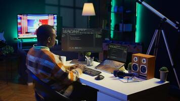 African american self employed developer in home office coding on his computer at workstation. Focused IT specialist doing contracted job from apartment, writing lines of code at desk. Camera B. photo