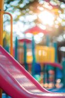 vertical image close-up red children's slide on a colorful bright playground selective focus photo