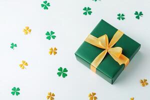 close-up green gift box with gold ribbon surrounded by little green shamrocks on white background with copy space, st Patrick day card photo
