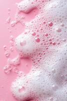 vertical image top view close-up white soap foam and bubbles on clean pink background photo