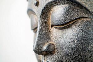 close-up serene Buddha face with eyes closed statue on white background photo