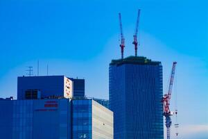A time lapse of moving cranes on the top of building behind the blue sky in Tokyo photo