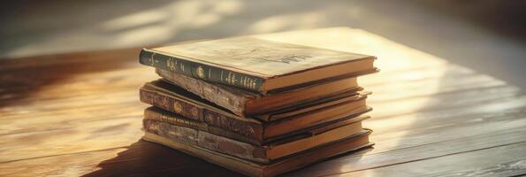 Stack of old books on wooden table with sunlight filtering through photo
