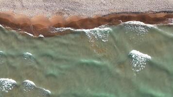 Aerial Top view Waves and Sandy Beach Aerial, A close-up aerial view of gentle waves rolling onto a sandy beach shoreline. video