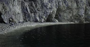 Secluded beach with rocky cliffs and calm water at twilight video