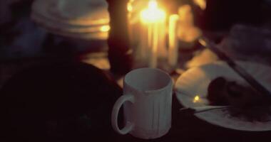 Warm cup resting on table surrounded by soft candlelight at dusk video